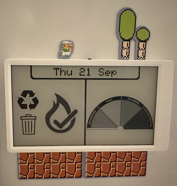 Photo of an M5Paper device, displaying rubbish and recycling icons, the date, and fire risk/ban information.